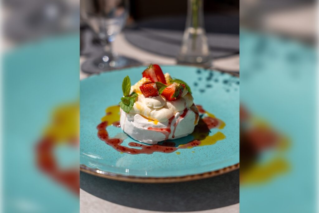 Beza Pavlova z kremem i owocami – deser widziany z boku w Restauracji Artemida Ustroń